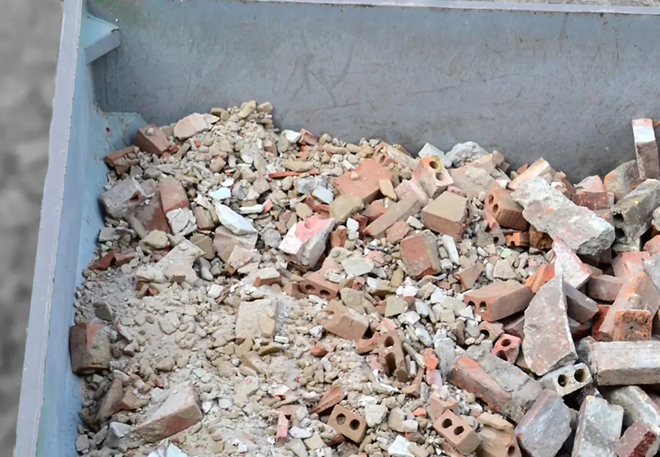 Puinafval container gevuld met bakstenen en betonpuin na het slopen van een muur